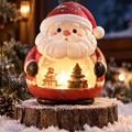 Front view of a light-up Santa Claus decoration with a red suit, white beard and glowing miniature Christmas scene