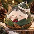 Front view of a smiling Christmas cat with a green pom-pom hat, red berries and a leafy brown nest-shaped base